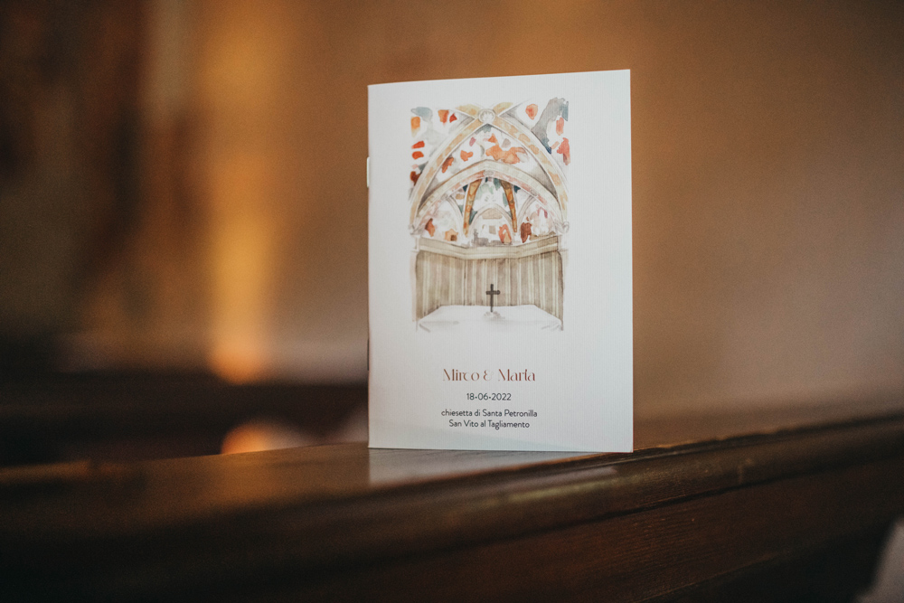 Foto del libretto della messa, realizzato appositamente per il matrimonio, la copertina oltre ai nomi degli sposi, la data e l'indirizzo della chiesetta di Santa Petronilla dove &egrave; avvenuto il rito religioso, ha un dipinto realizzato in acquerello della cupola della stessa chiesetta, che non a caso ha una dominante dei colori scelti per il matrimonio, dal ruggine fino all'arancione