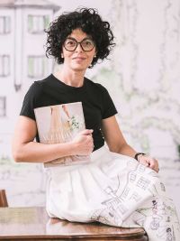 wedding planner Maria Mayer foto in primo piano di Maria seduta su un tavolo con in mano un libro di matrimoni